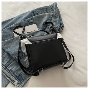 Detailed view of white lace trim on a black leather handbag with silver metal hardware