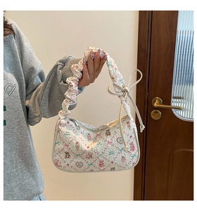 Detail of cream crossbody bag featuring cartoon bear patterns and ruffled handle straps
