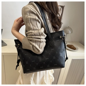 Detail of black printed tote bag featuring side drawstrings and gold hardware accents