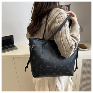 Détail d'un sac cabas noir avec motif monogramme et glands dans une scène de style de vie