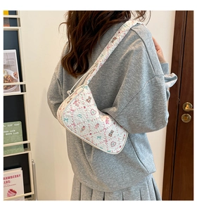 Detail of white pleated shoulder bag with cute cartoon bear and strawberry prints