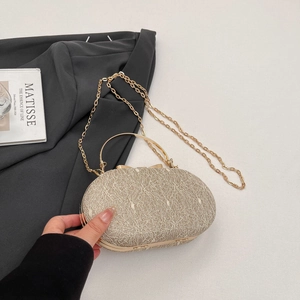 Détail d'une pochette de soirée dorée avec texture dentelle et poignée métallique