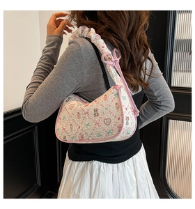 Detail of white moon bag featuring pink cartoon prints and a pleated bow shoulder strap