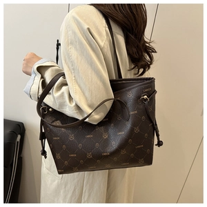 Detail view of brown tote bag featuring luxury monogram pattern and side drawstring design