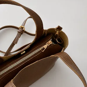 Detail of brown litchi pattern leather bucket bag with premium gold zipper and hardware