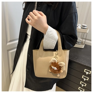 Dettaglio della borsa beige in pelle martellata con un simpatico ciondolo mostro di peluche