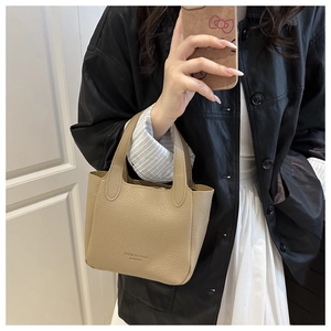 Close-up of beige lychee leather handbag with printed text and double handle design