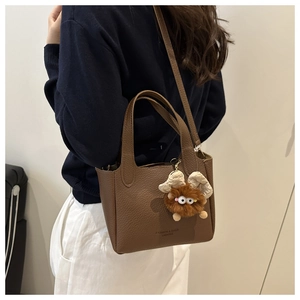 Dettaglio borsa a secchiello in pelle marrone scuro con simpatico ciondolo mostro di peluche