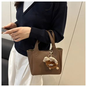 Détail du sac à main marron avec texture litchi et charmant pendentif monstre en peluche