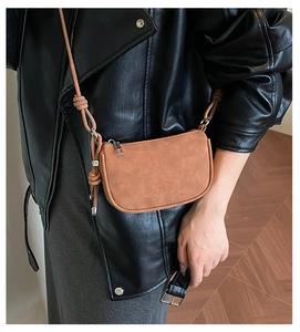 Detail of tan matte saddle bag with logo embossing and knotted shoulder strap detail