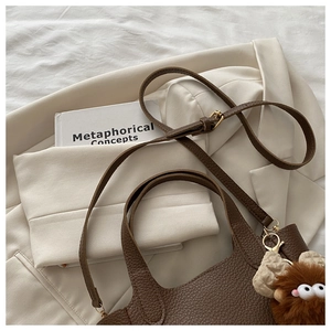 Dettaglio borsa tote in pelle martellata marrone scuro con ciondolo e tracolla regolabile