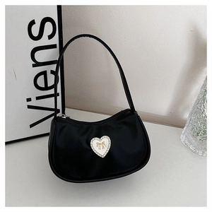 Close-up of black crescent bag featuring a white heart patch with a golden bow detail
