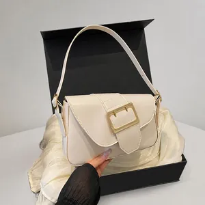 Detail of beige minimalist baguette bag with premium gold metal clasp on gift packaging