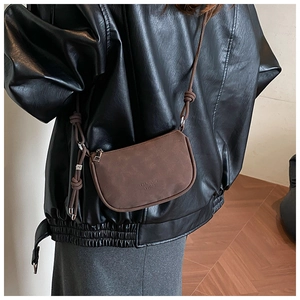 Detail of vintage brown leather crossbody bag with adjustable strap and embossed logo