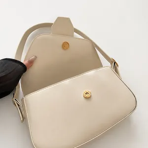 Close-up of high-quality gold magnetic buckle on off-white faux leather shoulder bag
