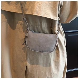Close-up of minimalist grey pebbled leather crossbody bag with embossed logo detail