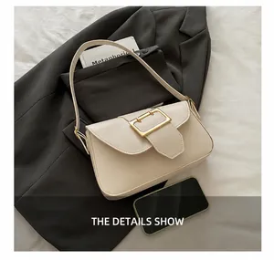 Detail shot of a beige matte leather baguette bag with a large golden metal buckle