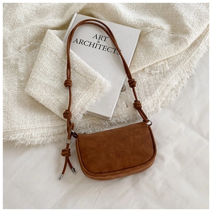 Detail of brown suede crossbody bag showing textured finish and knotted strap details