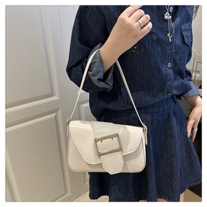 Sac sous le bras chic en cuir crème avec boucle dorée porté par un mannequin