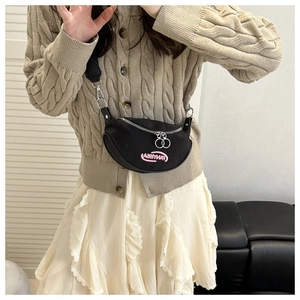 Detail of black crescent crossbody bag featuring pink embroidery and silver dual zippers
