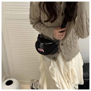Detail of black sporty crossbody bag with twin ring zippers and pink logo patch