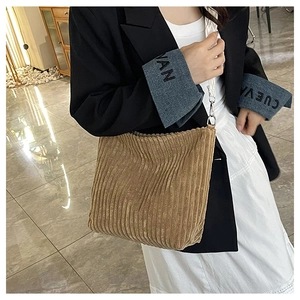 Détail d'un sac cabas en velours côtelé kaki avec bandoulière blanche et boucle