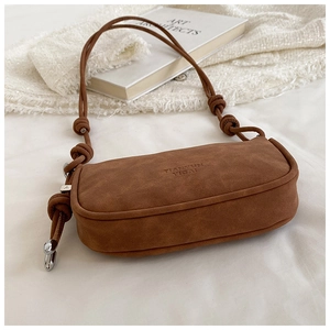 Detail of brown suede tote bag featuring embossed logo and textured rope shoulder strap