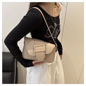 Gros plan d'un sac sous le bras beige avec boucle dorée et détails de bandoulière