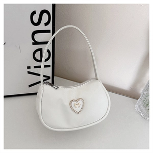 Detail of white crescent shoulder bag featuring a sparkling rhinestone heart decoration