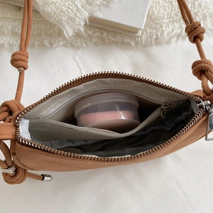 Macro view of a brown soft crossbody bag showing zipper closure and interior storage space