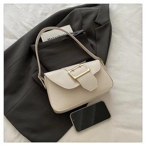Détail d'un sac à main élégant en cuir beige avec boucle dorée et décor de style