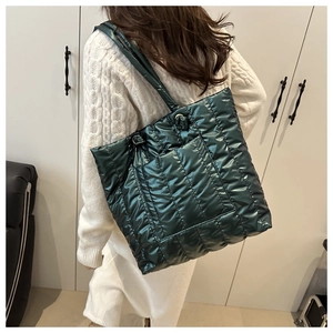 Detail of dark green quilted tote bag with metallic finish shown on shoulder in macro view