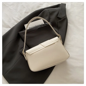 Détail du sac bandoulière blanc crème sur blazer gris avec boucle métallique dorée