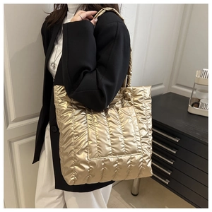 Quilted champagne gold tote bag shown on shoulder in a stylish lifestyle setting
