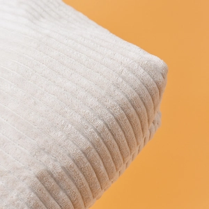 Gros plan sur la texture du velours côtelé beige montrant les rayures et le fini doux