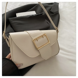 Détail d'un sac à bandoulière crème élégant avec boucle dorée carrée et surpiqûres fines