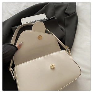 Détail du sac sous le bras en cuir blanc crème avec fermeture à boucle magnétique en métal