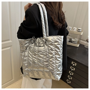 Detail of silver quilted tote bag showing metallic texture and reinforced shoulder straps
