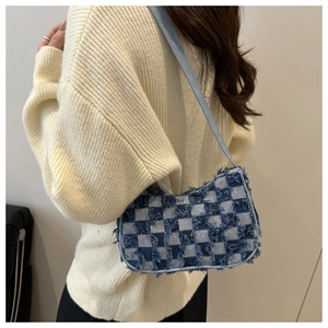 Close-up of blue checkerboard denim shoulder bag with frayed edges and smooth strap