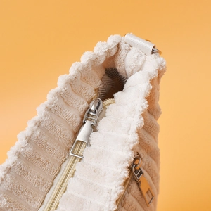 Gros plan détaillé sur la texture en velours côtelé et les fermetures éclair d'un sac beige