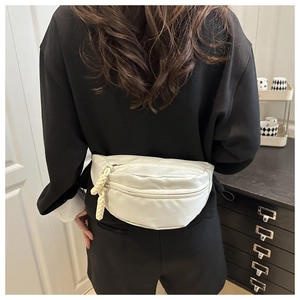 Detailed view of white nylon fanny pack with unique woven knot zipper on black outfit