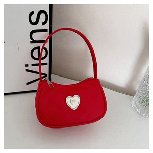 Detail of red hobo bag featuring a heart-shaped buckle with a gold bow and crystals