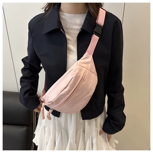Close-up of pink canvas waist bag with adjustable strap worn by model in casual style