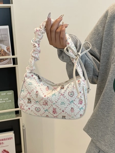 White pleated tote bag with cute cartoon prints and bow details shown in a lifestyle setting