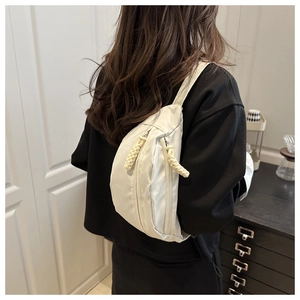 Detail van gebroken witte nylon crossbodytas met een unieke geweven touw ritstrekker