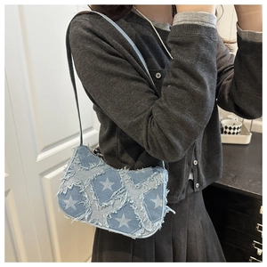 Detail of blue denim shoulder bag featuring white star patches and frayed edge texture