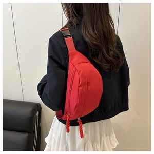 Red nylon waist bag with double zippers and woven pulls shown on a model's back