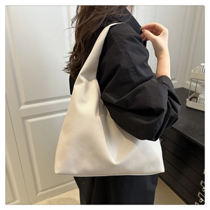 Detail of off-white tote bag showing pebbled leather texture and shoulder strap drop