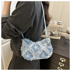 Détail du sac sous le bras en denim bleu clair avec patchwork d'étoiles et franges
