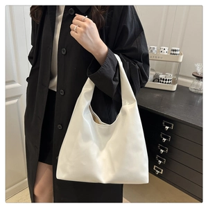 Gros plan d'un sac cabas blanc minimaliste en similicuir brillant avec de larges bandoulières